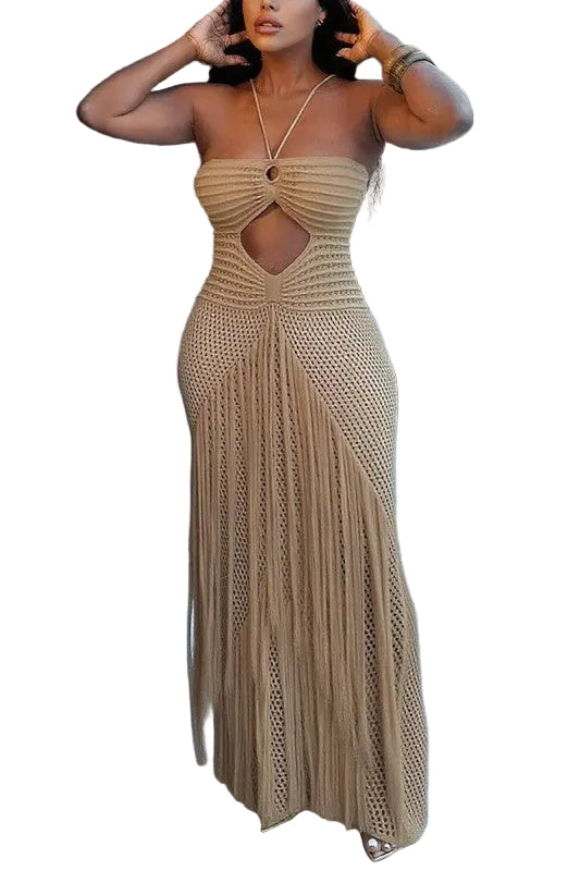 A woman modeling a sleeveless, strapless beige knit maxi dress with a cutout at the bust and long fringe-like knit detailing, standing on a tiled patio.