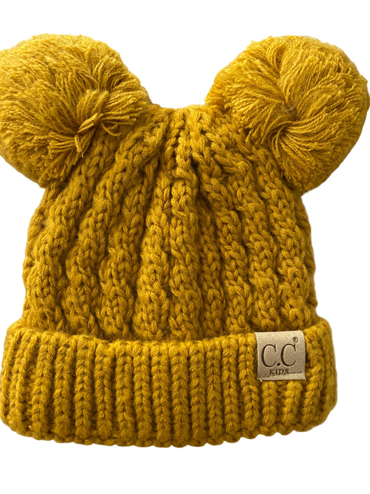 Yellow knitted beanie with pom-pom on a notebook